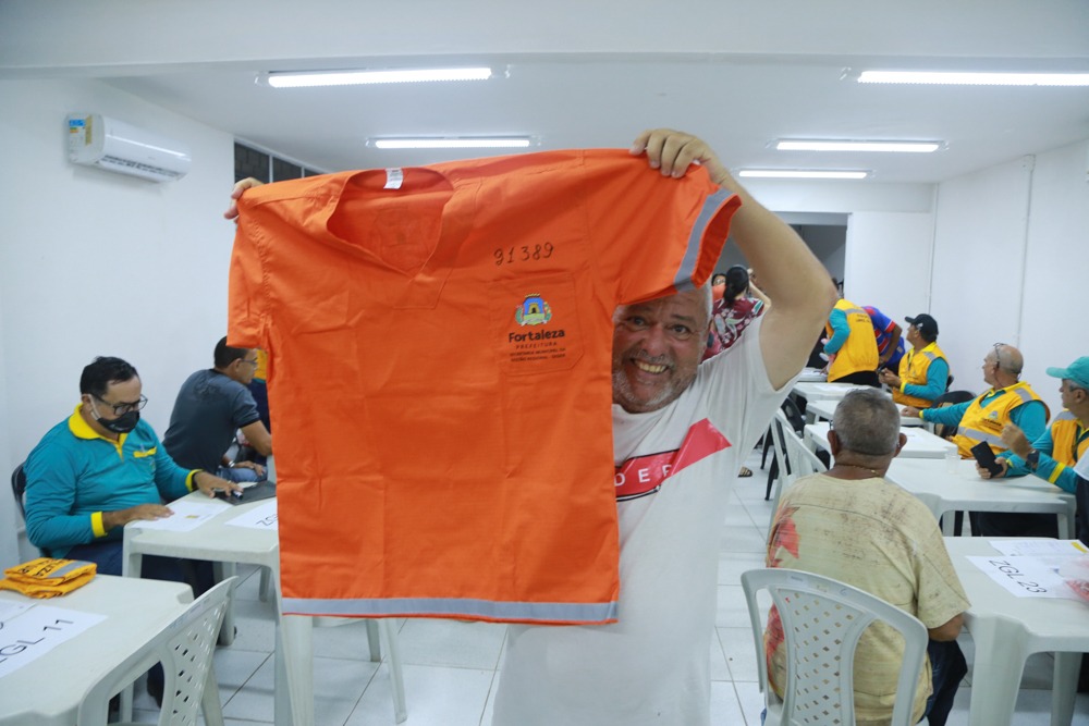 homem mostra o uniforme laranja de gari